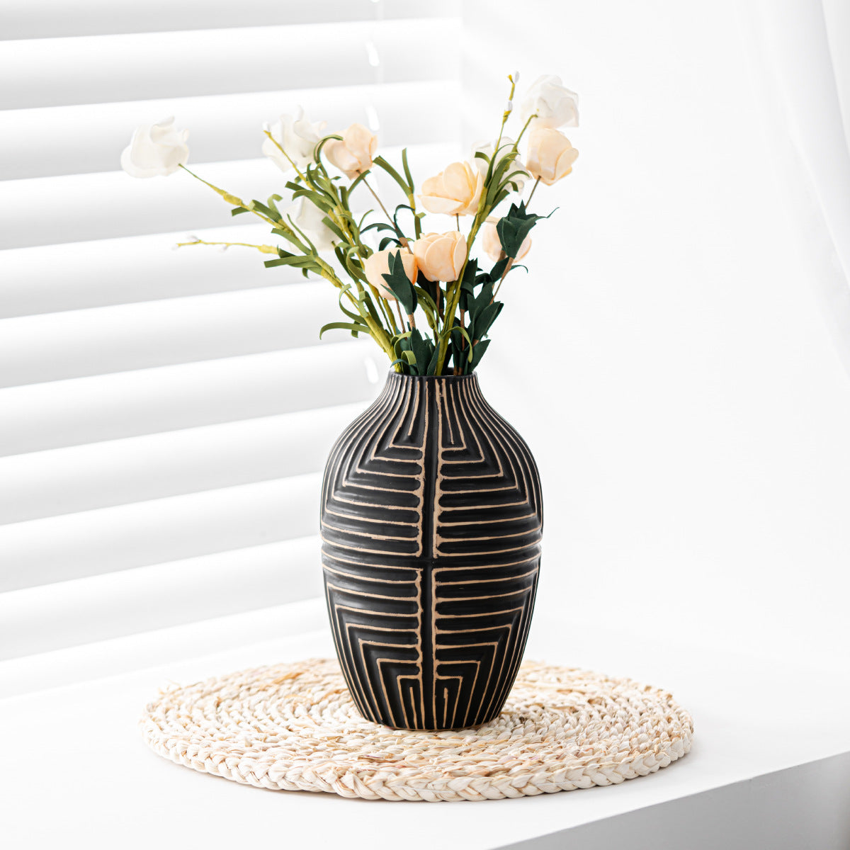 Decorative vase with geometric pattern on a white surface with flowers.