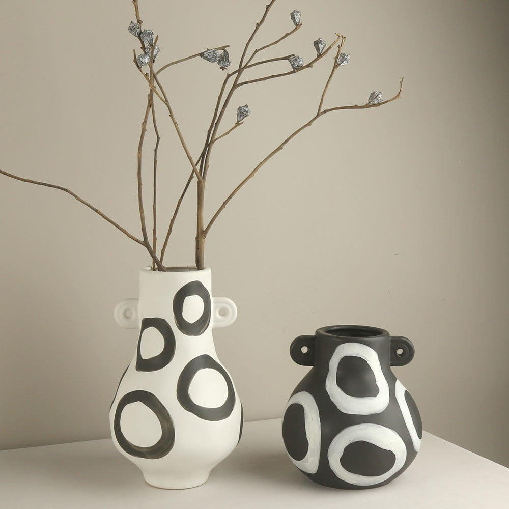 Two ceramic vases with black and white pattern on a neutral background