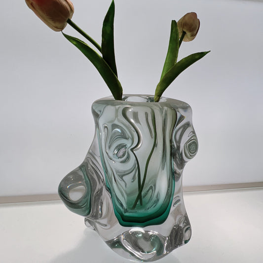 Glass vase with abstract design holding flowers on a white background