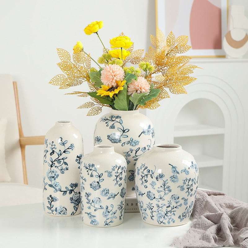 Set of floral-patterned vases with a bouquet of flowers on a white surface.