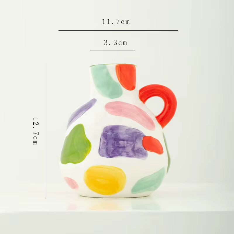Colorful ceramic pitcher with abstract patterns and measurements on a white background