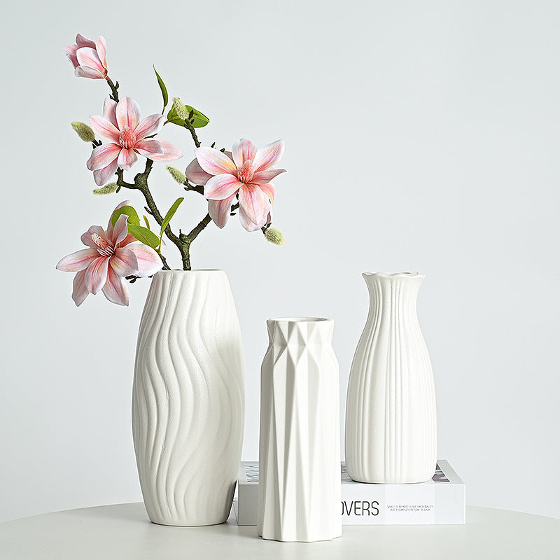 Set of three white ceramic vases with wavy design on a light gray background