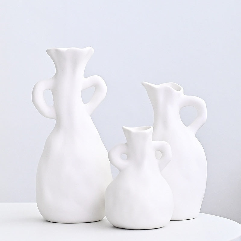 Three white ceramic vases of different shapes on a light gray background