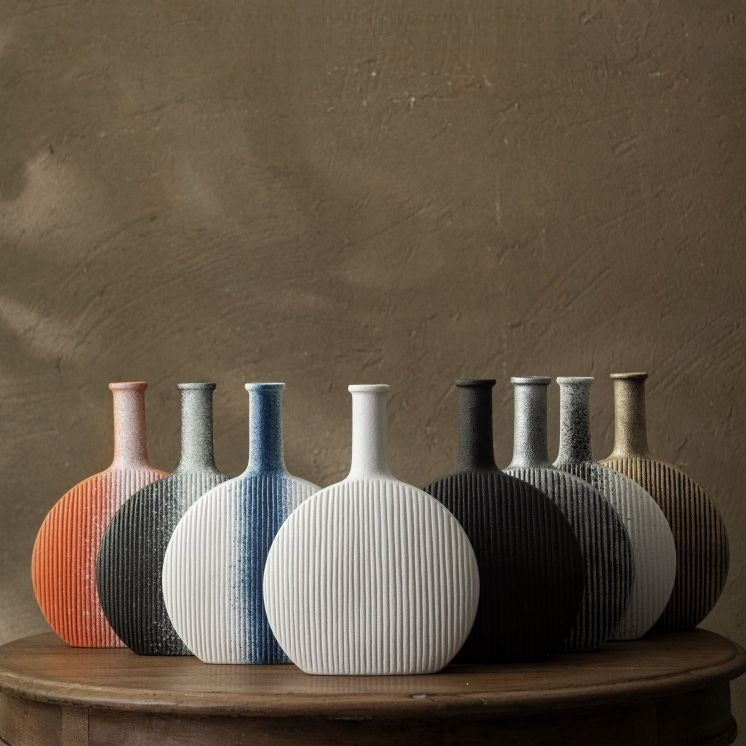Set of ceramic vases in various colors on a wooden surface with a brown background
