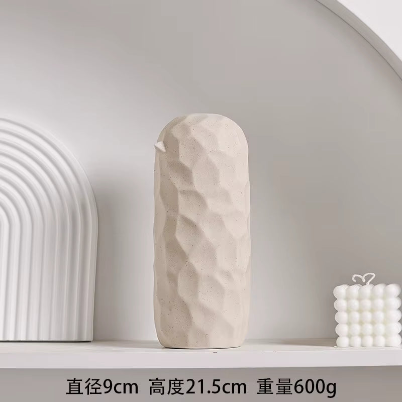 Beige textured vase on a white shelf with minimal background