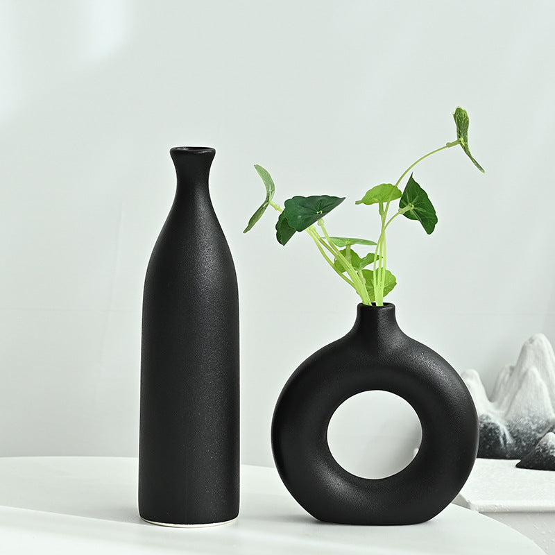Two black vases on a white surface with a light gray background