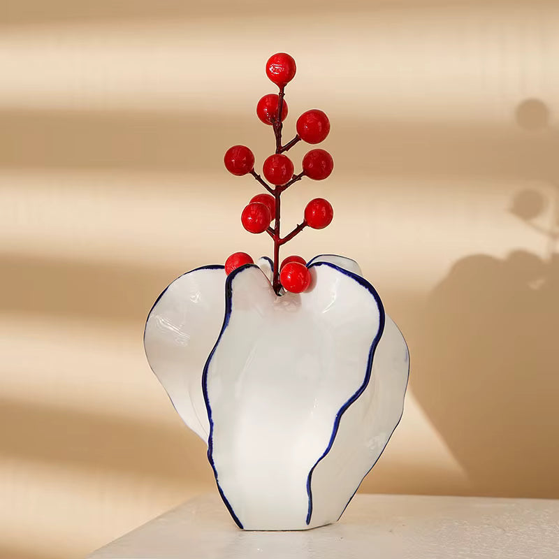 White vase with blue rim holding red berries against a beige background