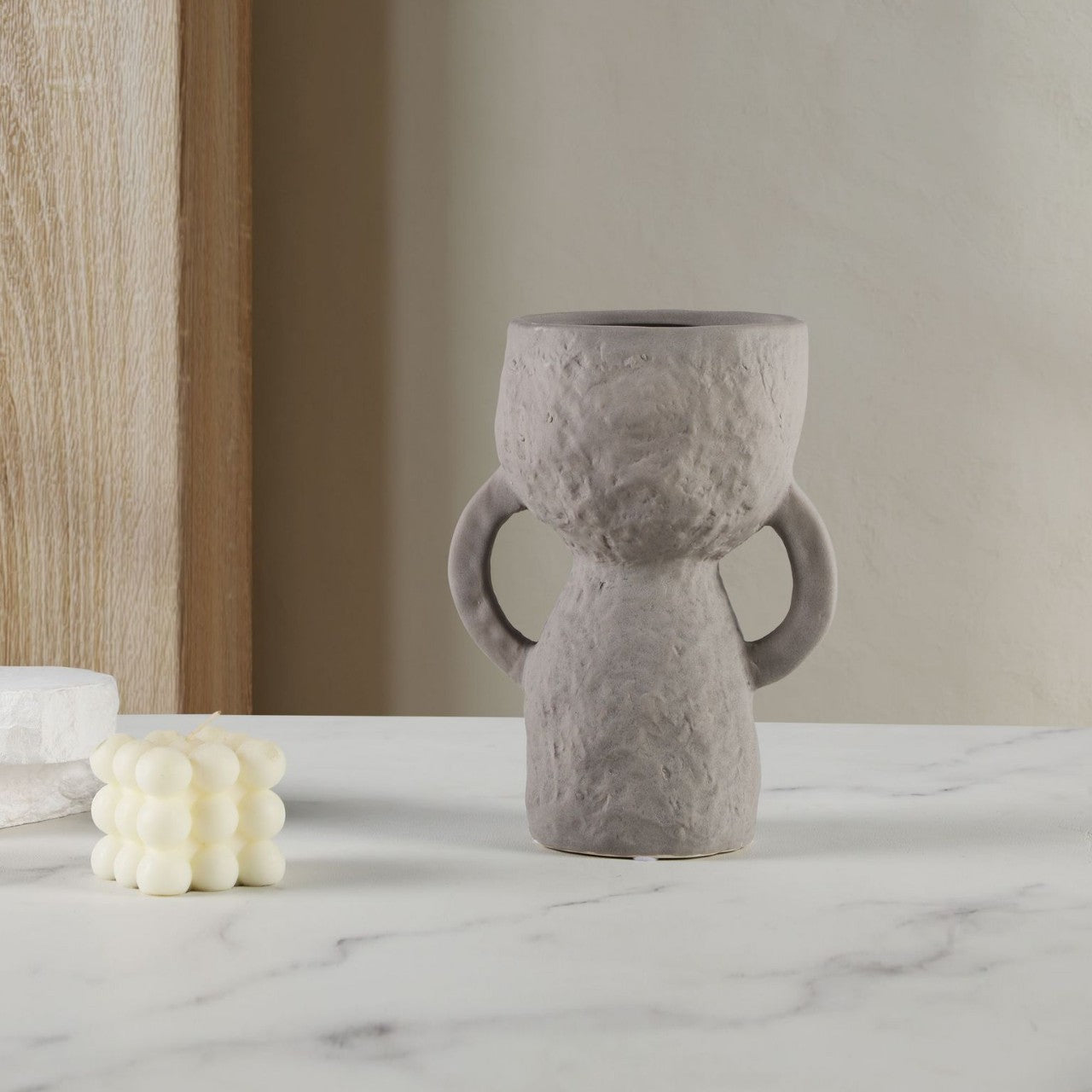 Gray textured vase on a marble surface with a neutral background