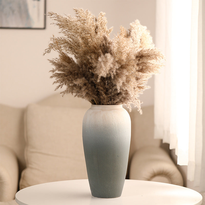 Gray vase with dried plants on a table in a living room setting
