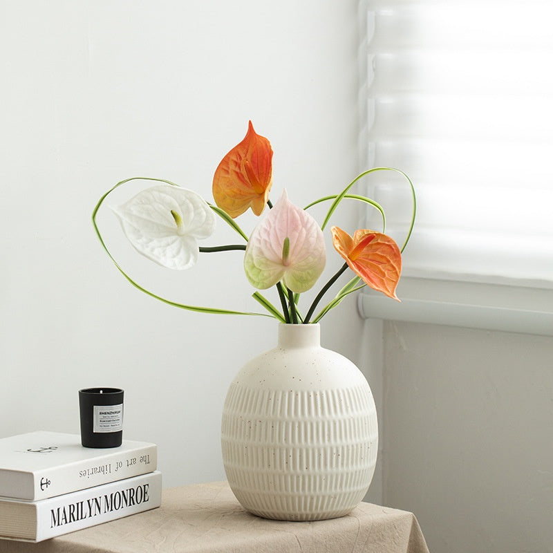 White textured vase with colorful flowers on a table against a light background