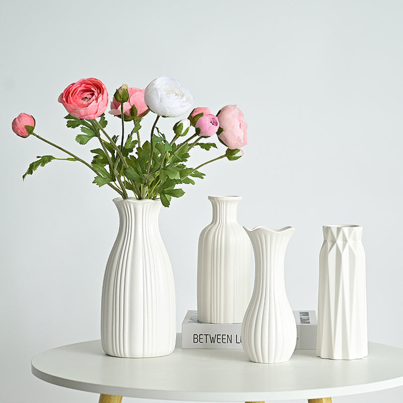 Set of white vases with a bouquet of pink and white flowers on a light gray background