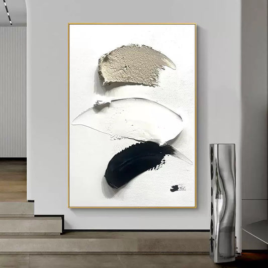 Abstract art piece with black and white brush strokes in a gold frame on a wall.