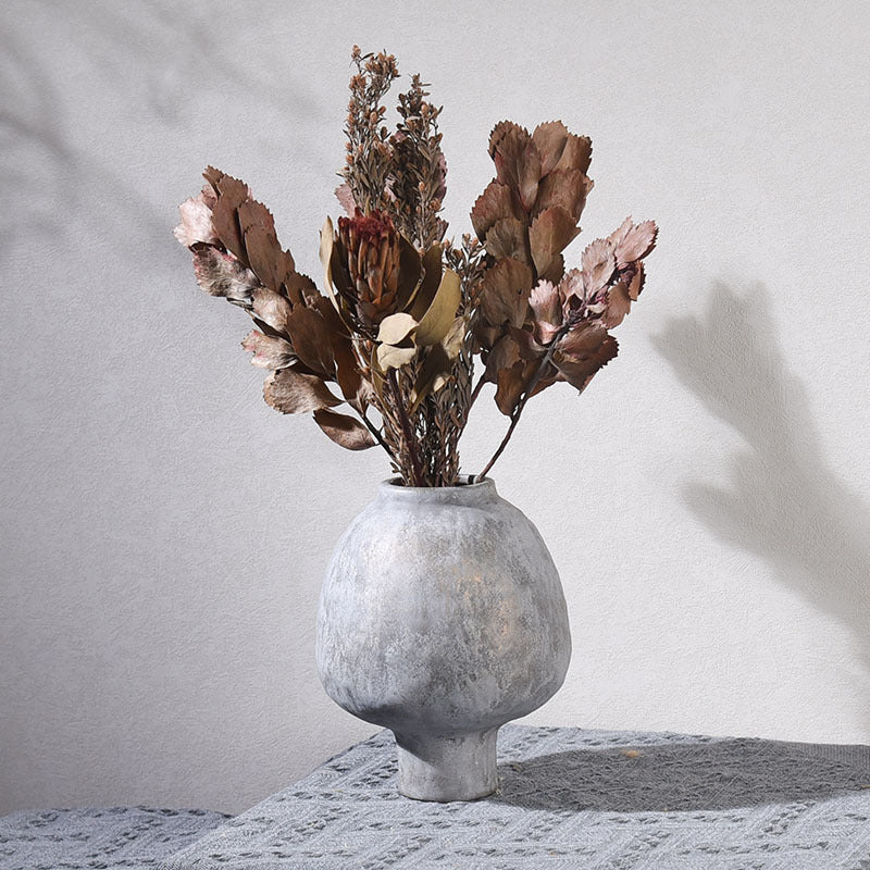Decorative vase with dried flowers on a textured surface