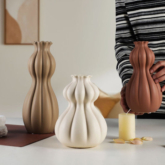 Three ceramic vases on a table with a person holding one of them.