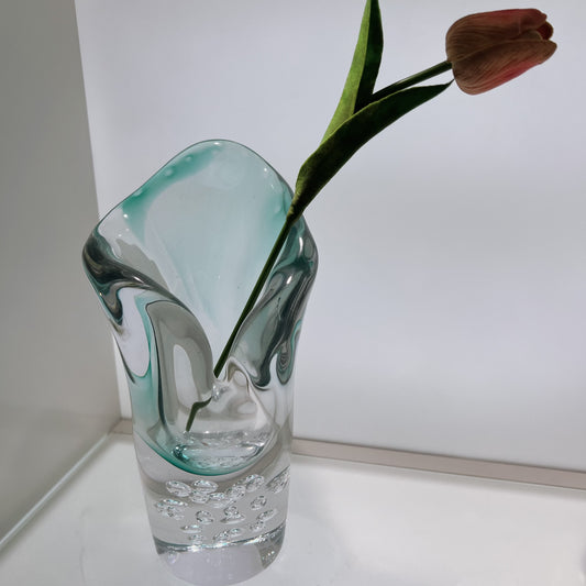Glass vase with a single tulip on a white surface