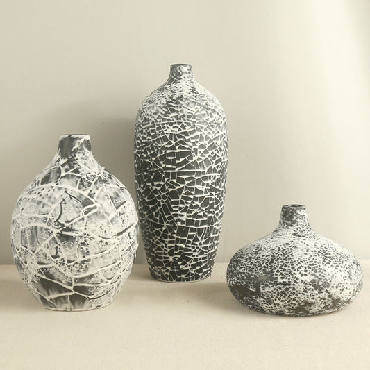 Three decorative vases with unique textures on a plain background