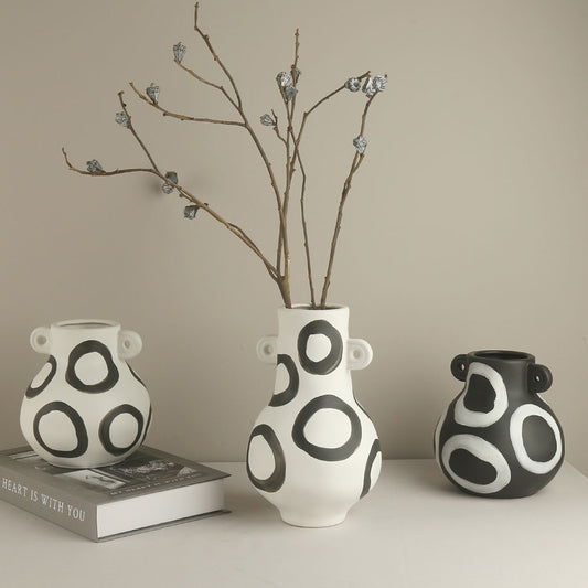 Three black and white patterned vases on a neutral background