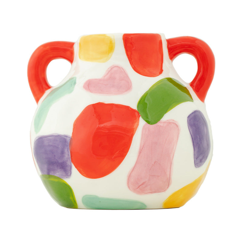 Colorful ceramic pitcher with abstract patterns on a white background