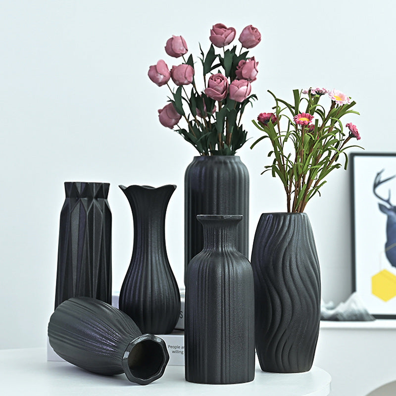 Set of black ceramic vases with floral arrangements on a light background