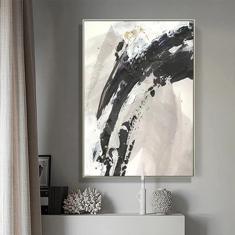 Abstract black and white painting on a gray wall with decorative items below.