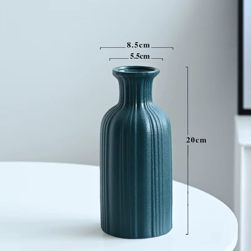 Teal ceramic vase with measurements on a white surface and light gray background