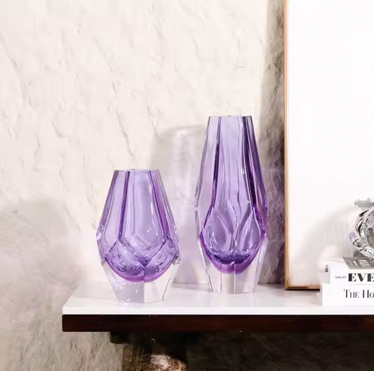 Two purple glass vases on a white surface with a neutral background
