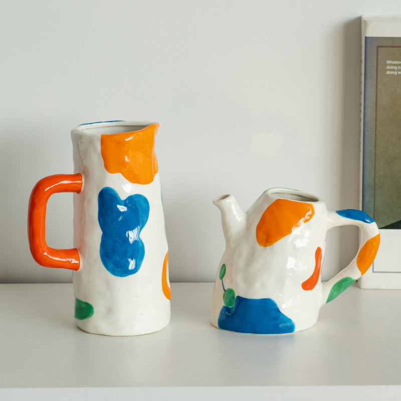 Two ceramic jugs with colorful abstract designs on a white surface.