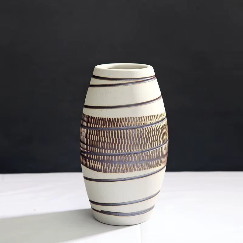 Ceramic vase with striped design on a white surface and black background