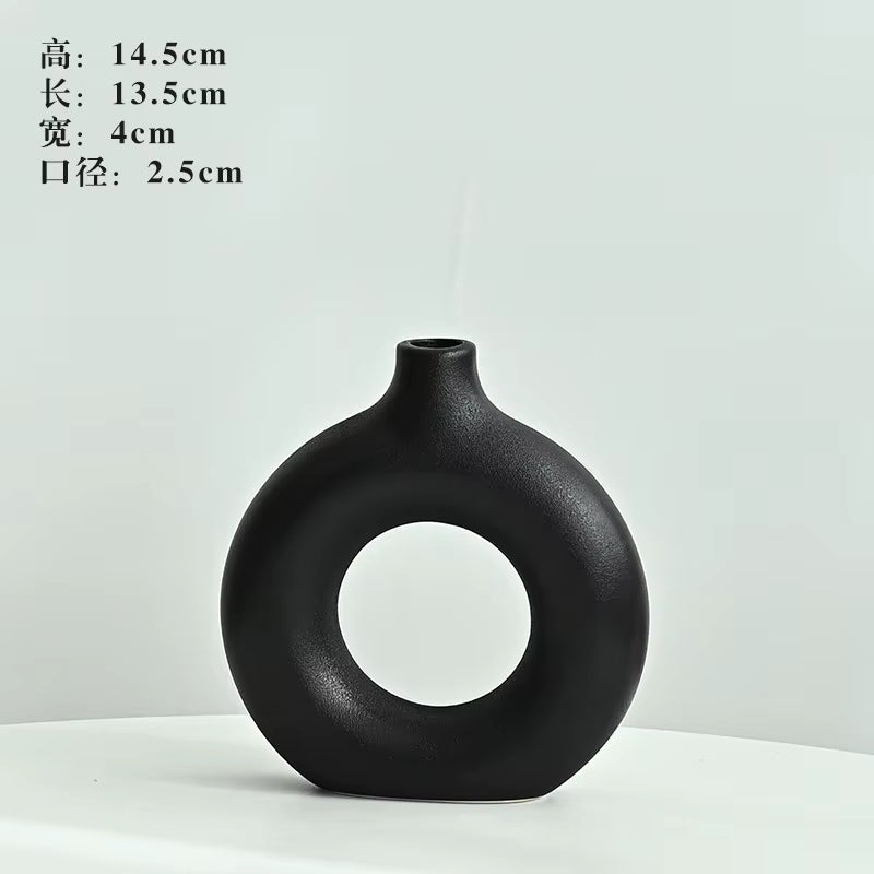 Black ceramic vase with circular design on a white background