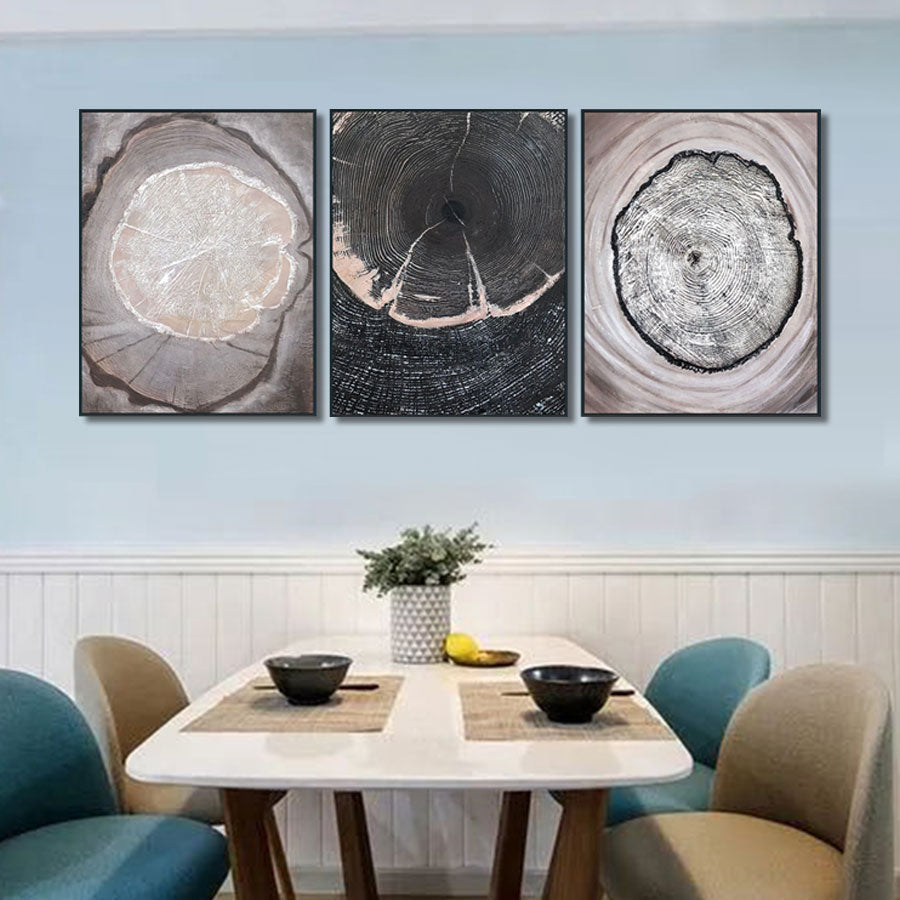 Three abstract wall art pieces on a light blue wall above a dining table.