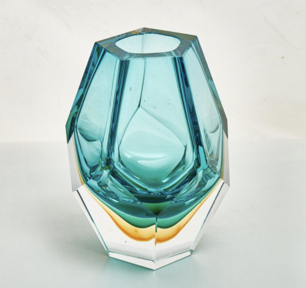 Teal glass vase with geometric design on a light gray background
