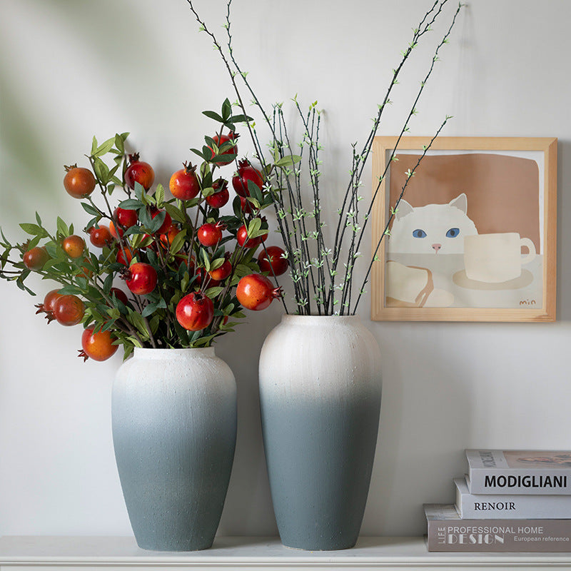Two vases with floral arrangements on a shelf, with a framed picture of a cat in the background.