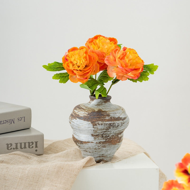 Decorative vase with orange flowers on a light surface