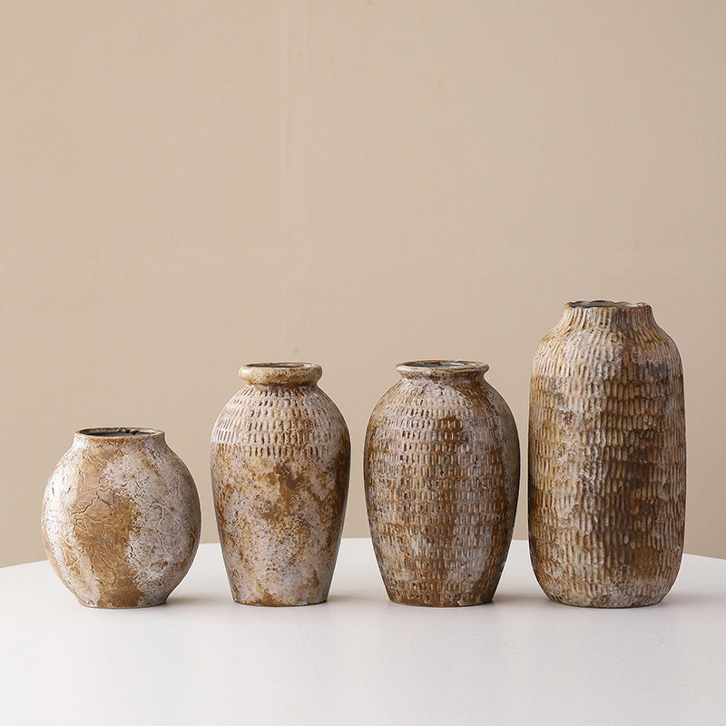Four rustic ceramic vases of varying sizes on a light surface with a beige background