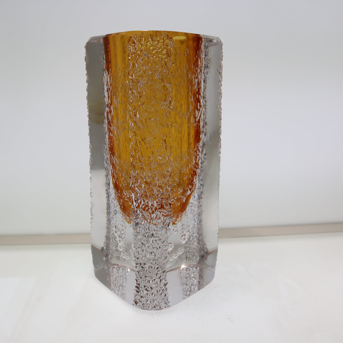 Glass vase with amber top and clear base on a white background