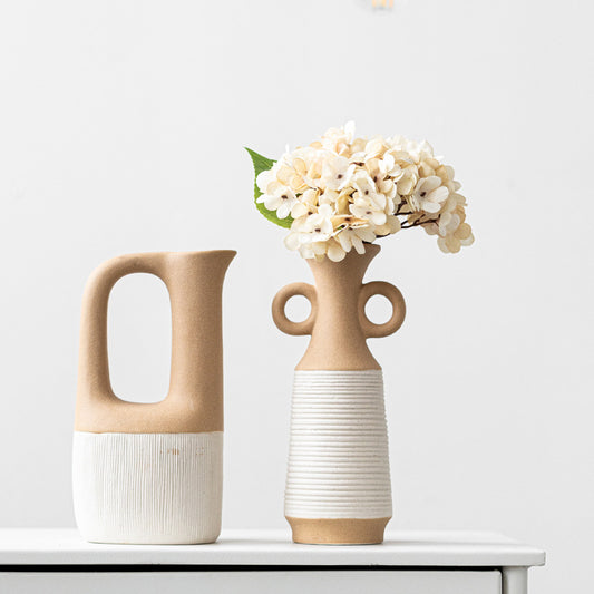 Two ceramic vases with handles on a white surface against a light gray background