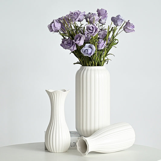 White ceramic vases with a bouquet of purple flowers on a light gray background