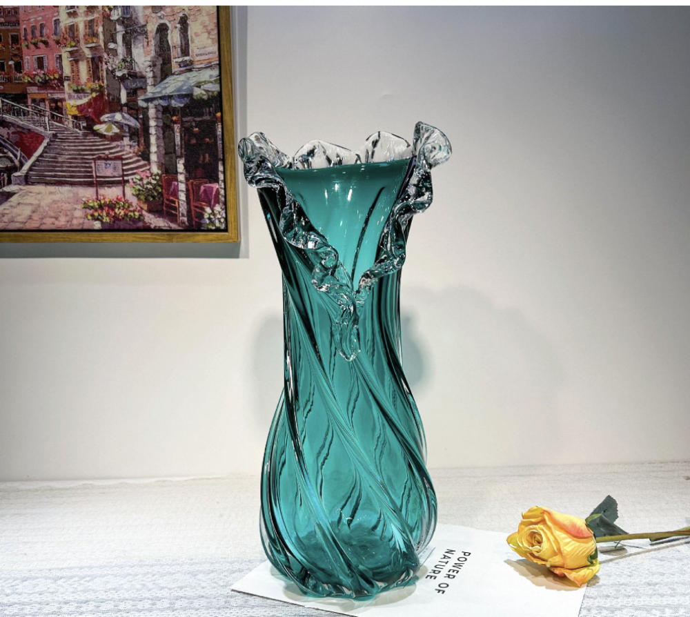 Turquoise glass vase on a surface with a painting in the background