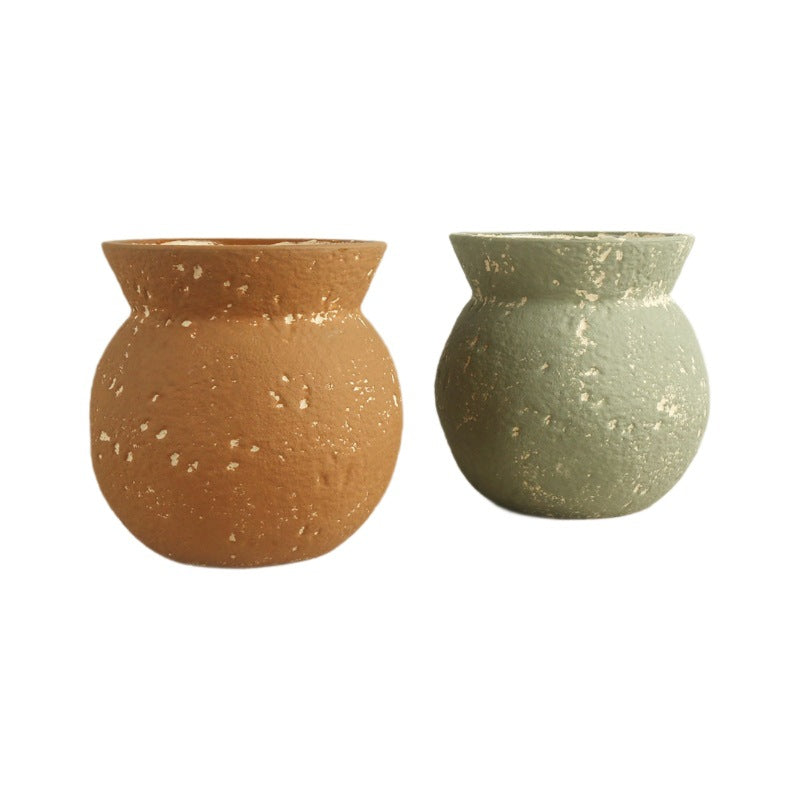 Two terracotta pots, one brown and one green, on a white background