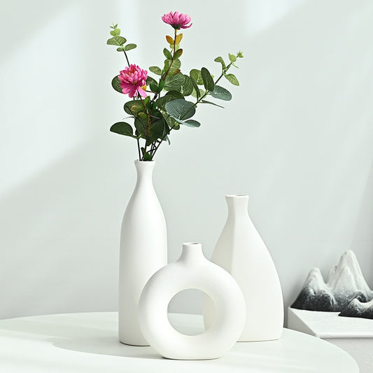 Set of white vases with a single white flower on a light gray background