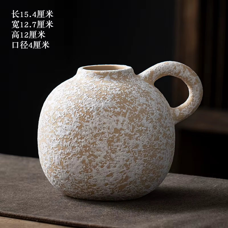Textured ceramic vase with a handle on a dark surface
