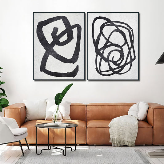 Modern living room with abstract black artwork on a white wall above a brown sofa.