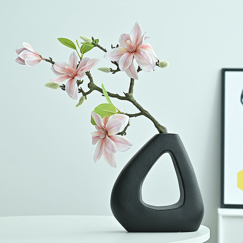 Black vase with pink flowers on a light blue background