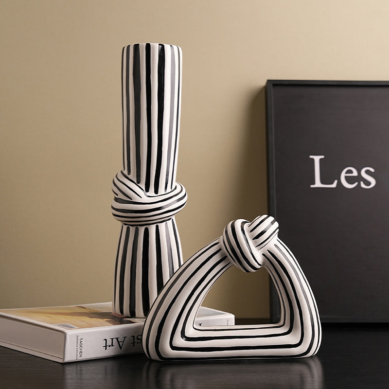 Black and white striped decorative items on a surface with a book and a black box in the background.