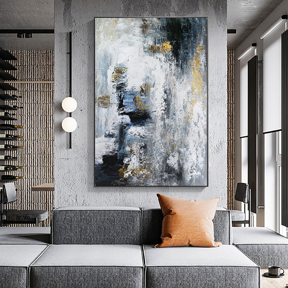 Abstract painting in a modern living room with a gray sofa and orange pillow.