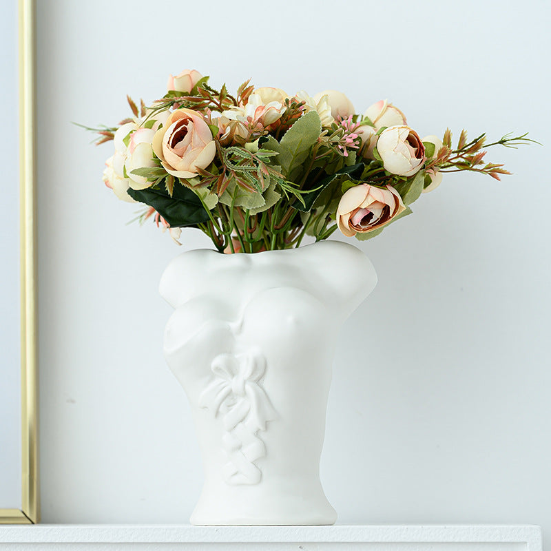 White face-shaped vase with flowers on a light blue wall