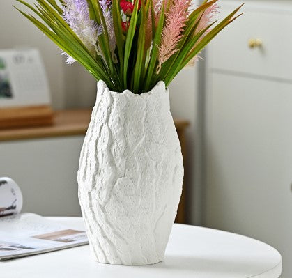 White textured vase with flowers on a surface