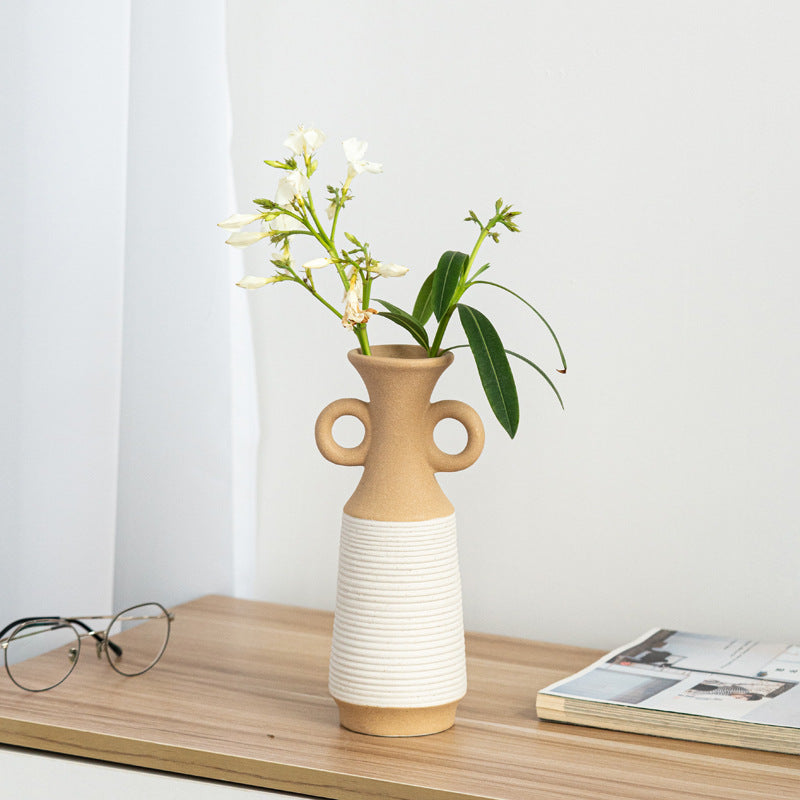 Beige and white vase with flowers on a wooden surface