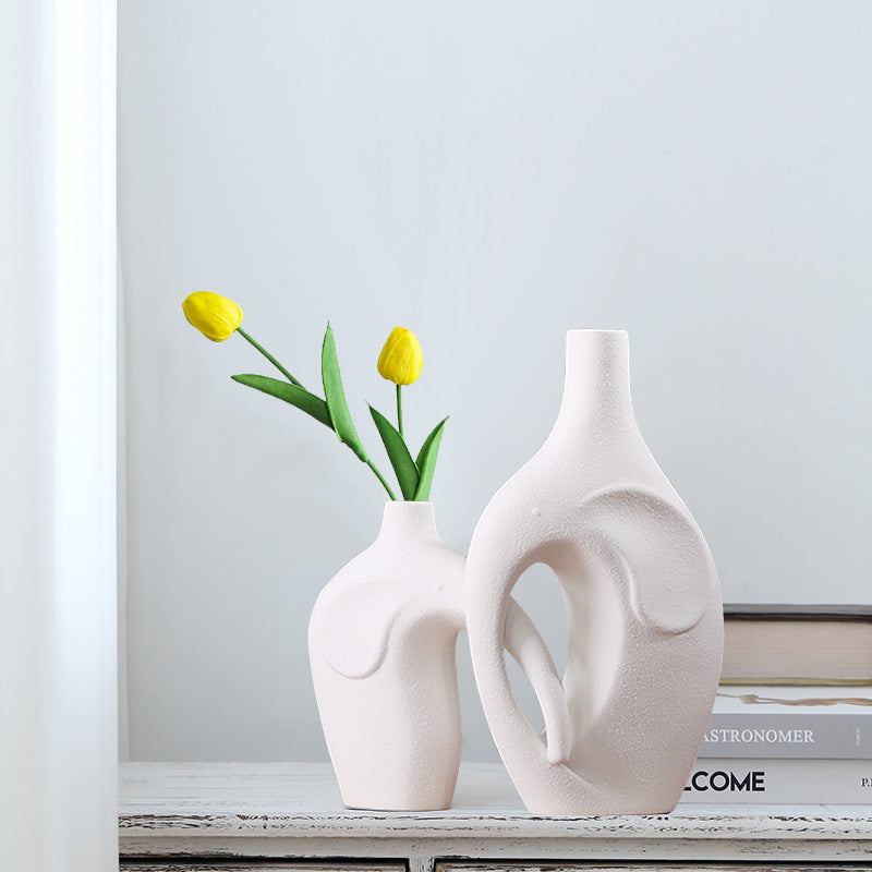 Two white ceramic vases with a single yellow tulip on a shelf.