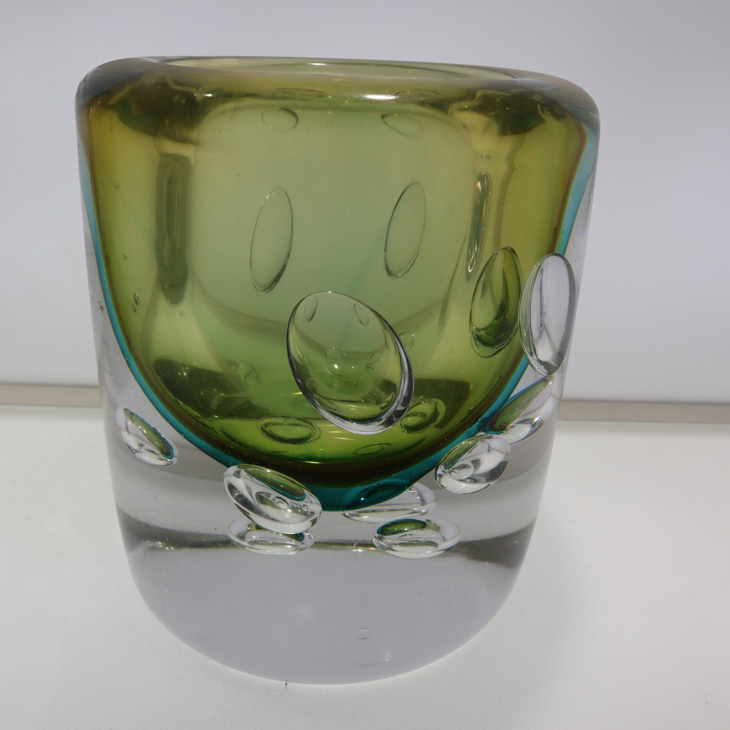 Green glass vase with bubble design on a white background